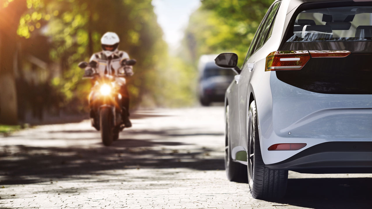 A motorcycle and a car passing each other