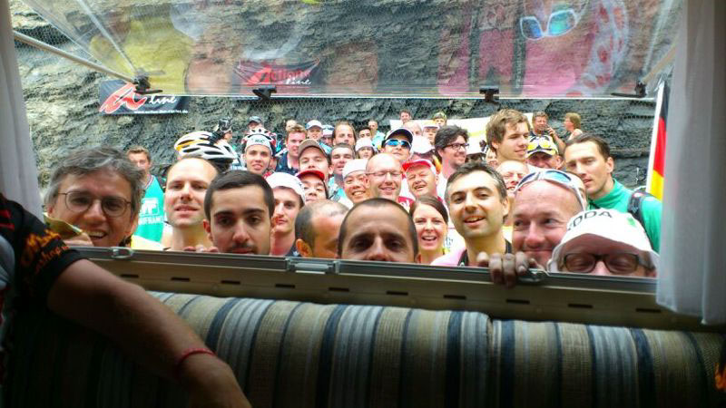 Fans trying to catch a glimpse of a TV showing the race in a motorhome at Alpe d’Huez